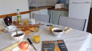 A breakfast table with croissants, coffee, juice, and a magazine.