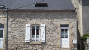 A stone building with two windows, each with white shutters.