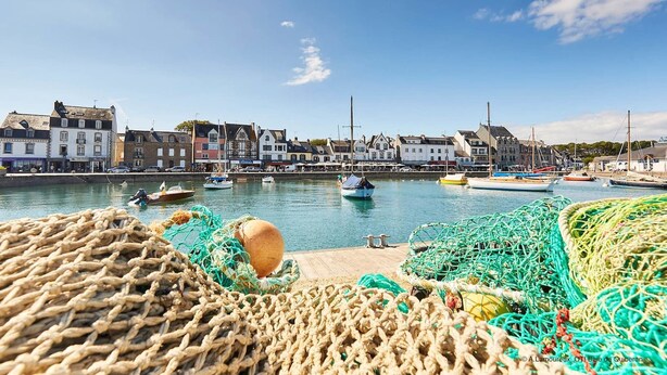 A harbor with boats and fishing nets, buildings along the waterfront, and a clear sky.
