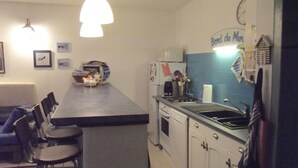 A compact kitchen with a central island, bar stools, a stove, and a refrigerator.