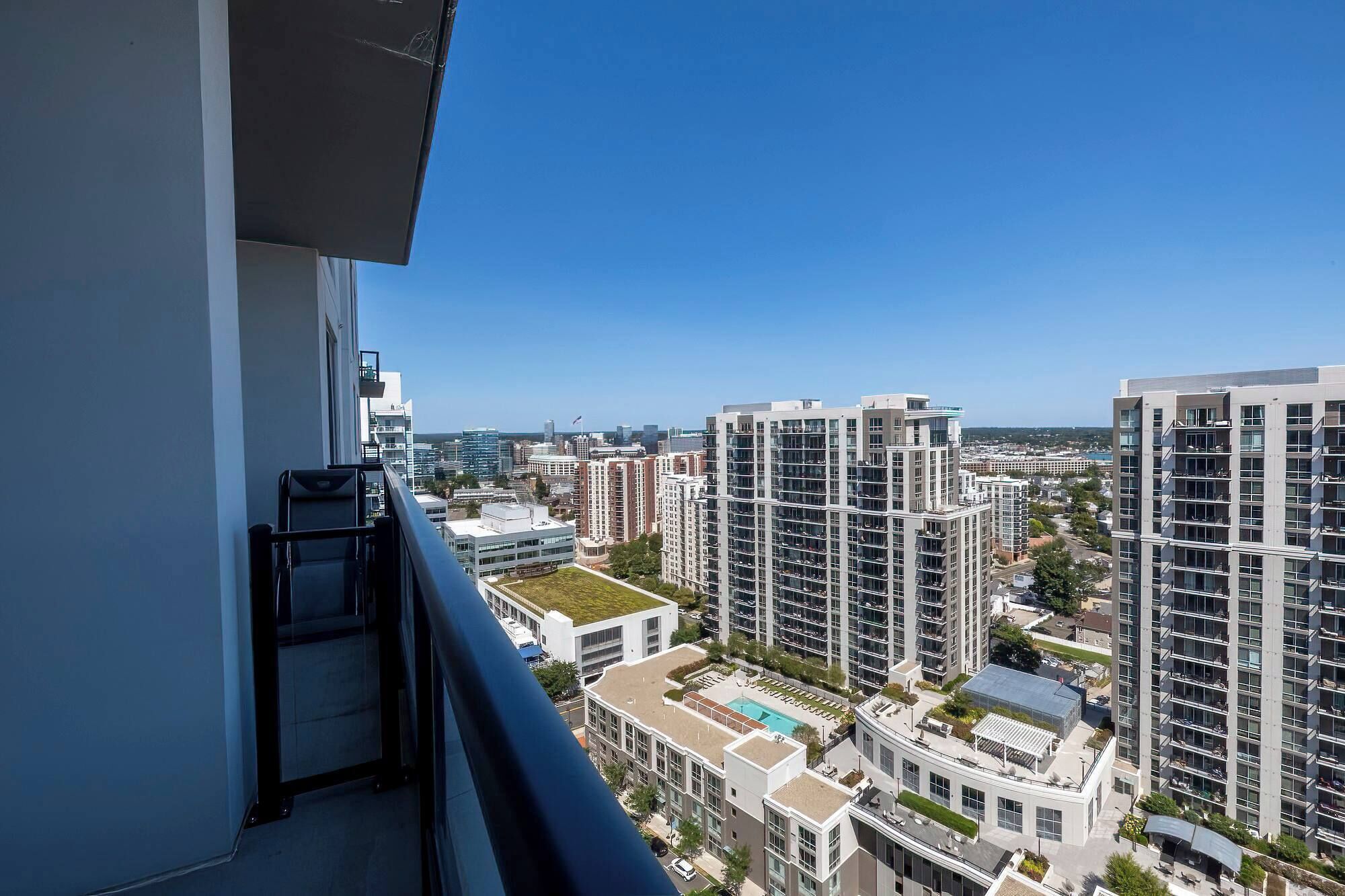 Un edificio de gran altura con varios balcones, una piscina en la azotea y vistas despejadas del paisaje urbano circundante.