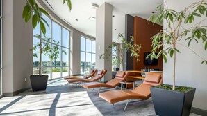Un espace d’attente moderne, doté de chaises longues, de grandes fenêtres et de plantes d’intérieur.