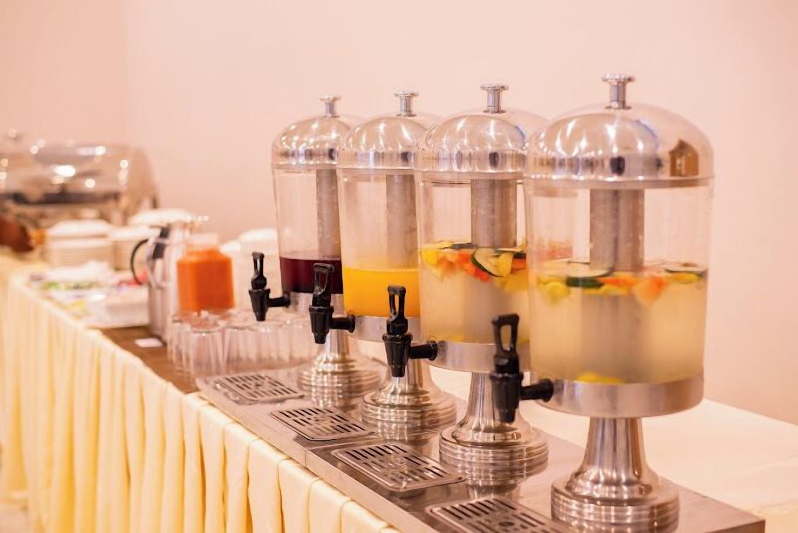 A buffet setup with multiple beverage dispensers and a variety of food items.
