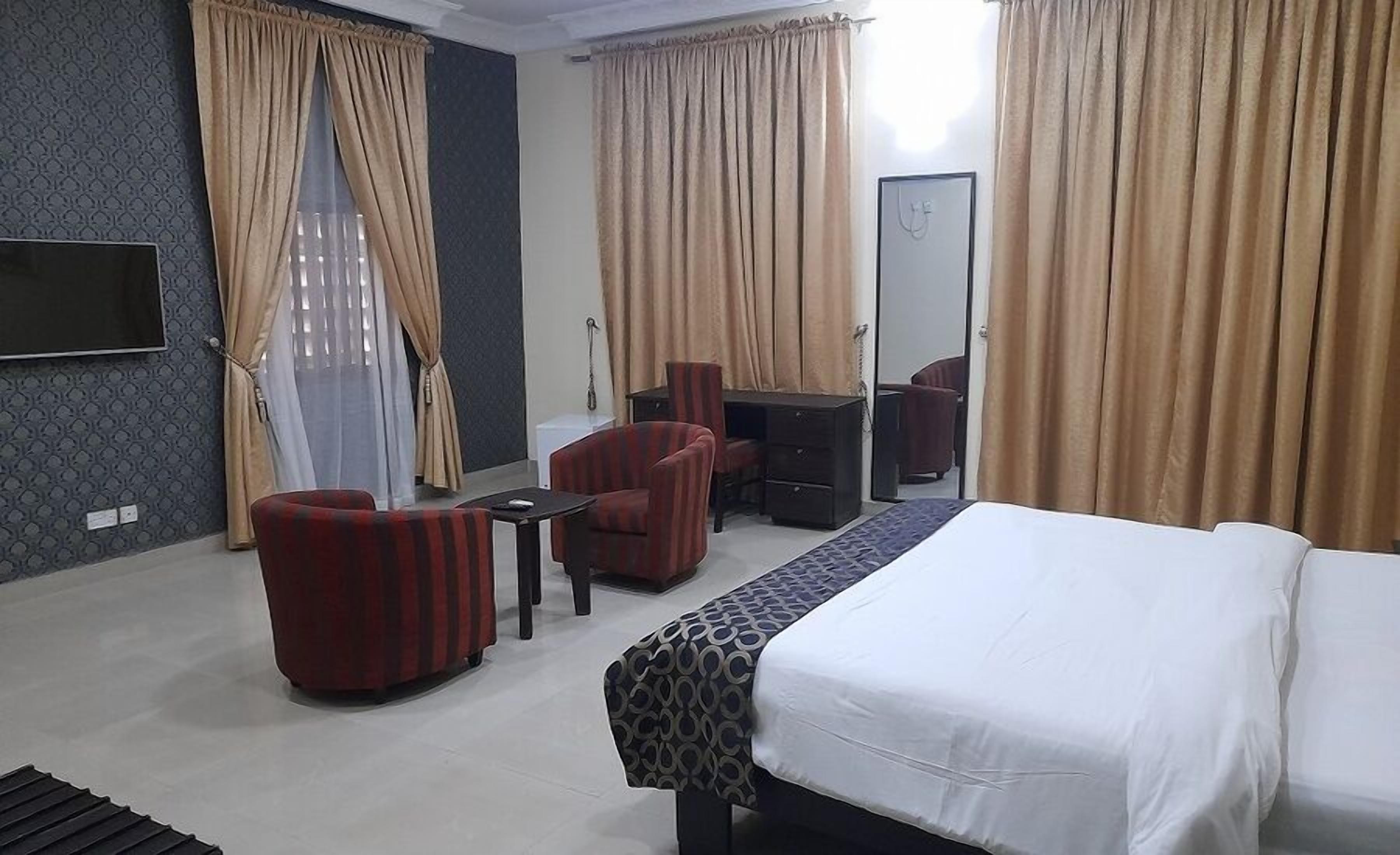 A hotel room with a bed, a desk, a chair, and a TV.