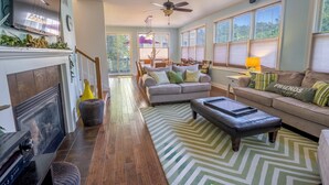 A spacious living room with a fireplace, a sofa set, a coffee table, and a dining area with chairs. - Hillside retreat in Beachwalk Resort for 10 (Michigan City)