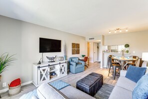 Un salon moderne comprenant un canapé, un pouf et un coin repas avec une table et des chaises.