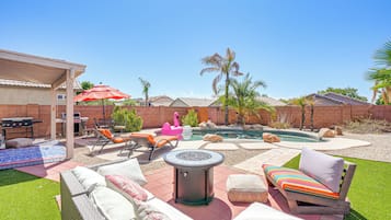 Un jardin avec une piscine, du mobilier d’extérieur et une pergola.