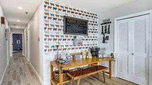 A hallway with a wooden bench, a wall-mounted sign listing seafood specials, and a door with louvered shutters. - Family Beach Days: Dog-friendly Cape Cod Condo (Dennis Port)
