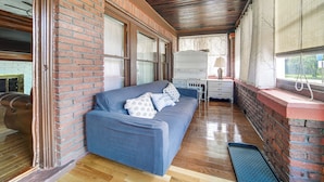 Ein Zimmer mit einem blauen Sofa, einem kleinen Tisch und einem Fenster mit Vorhängen.