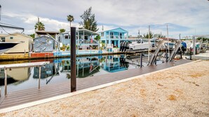 A marina with boats docked, a wooden deck, and a blue house with a balcony. - Canal-front Key Largo Retreat w/ Community Beach! (Key Largo)