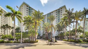 A hotel with multiple floors, palm trees, and a clear sky. - Hollywood Condo w/ Beach Access - Walk to Shore! (Hollywood)