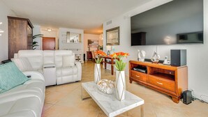 A modern living room with a white sofa, a marble coffee table, and a wooden entertainment unit. - Hollywood Condo w/ Beach Access - Walk to Shore! (Hollywood)