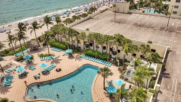 An aerial view of a resort with a swimming pool, beach, and palm trees. - Hollywood Condo w/ Beach Access - Walk to Shore! (Hollywood)