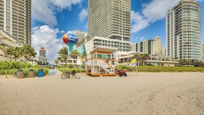 A beach with a lifeguard tower, high-rise buildings, and a sign for the Halland Beach. - Hollywood Condo w/ Beach Access - Walk to Shore! (Hollywood)