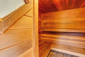 A wooden sauna with a sloped ceiling and wooden benches.