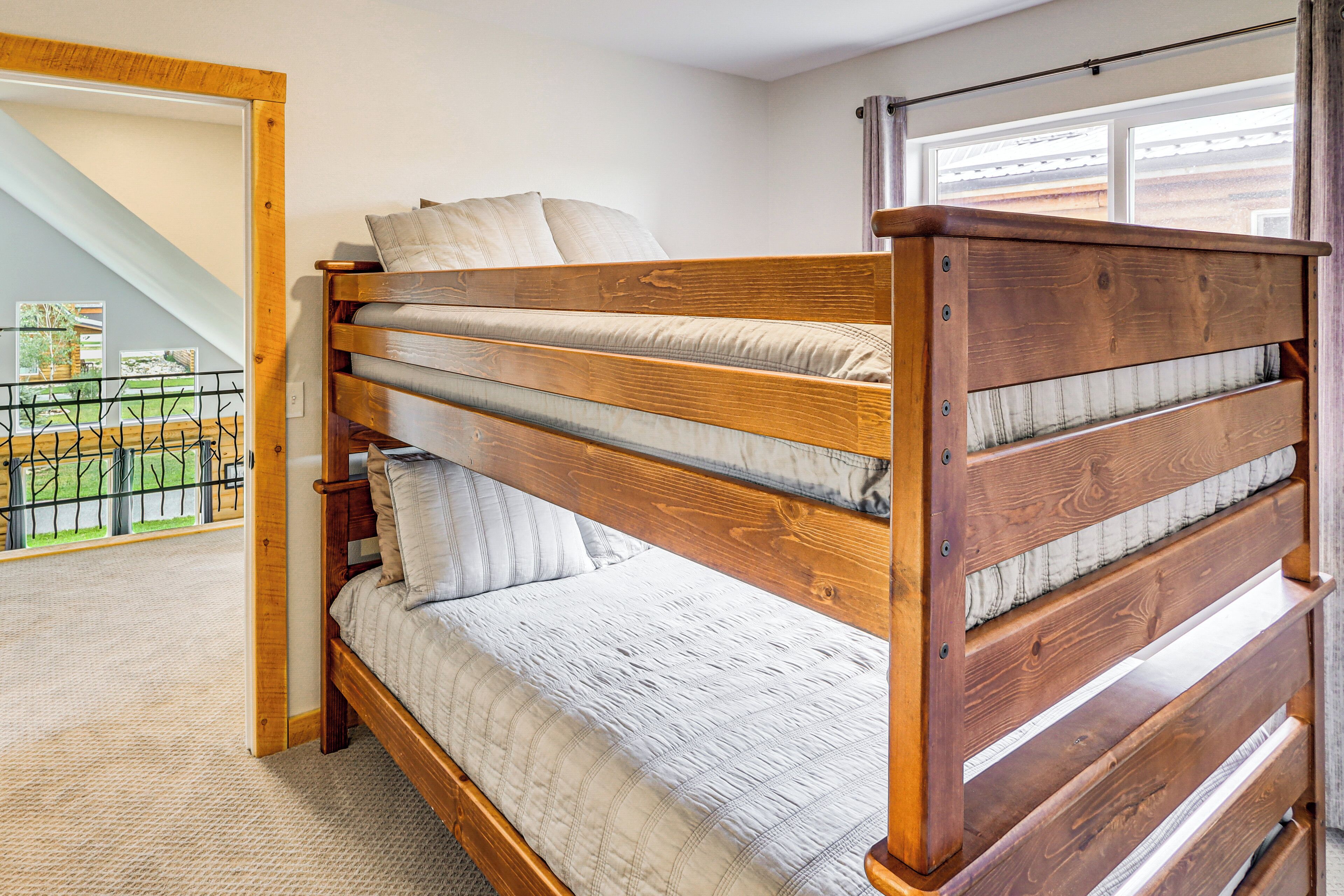 A wooden bunk bed with a view of a balcony and a window.