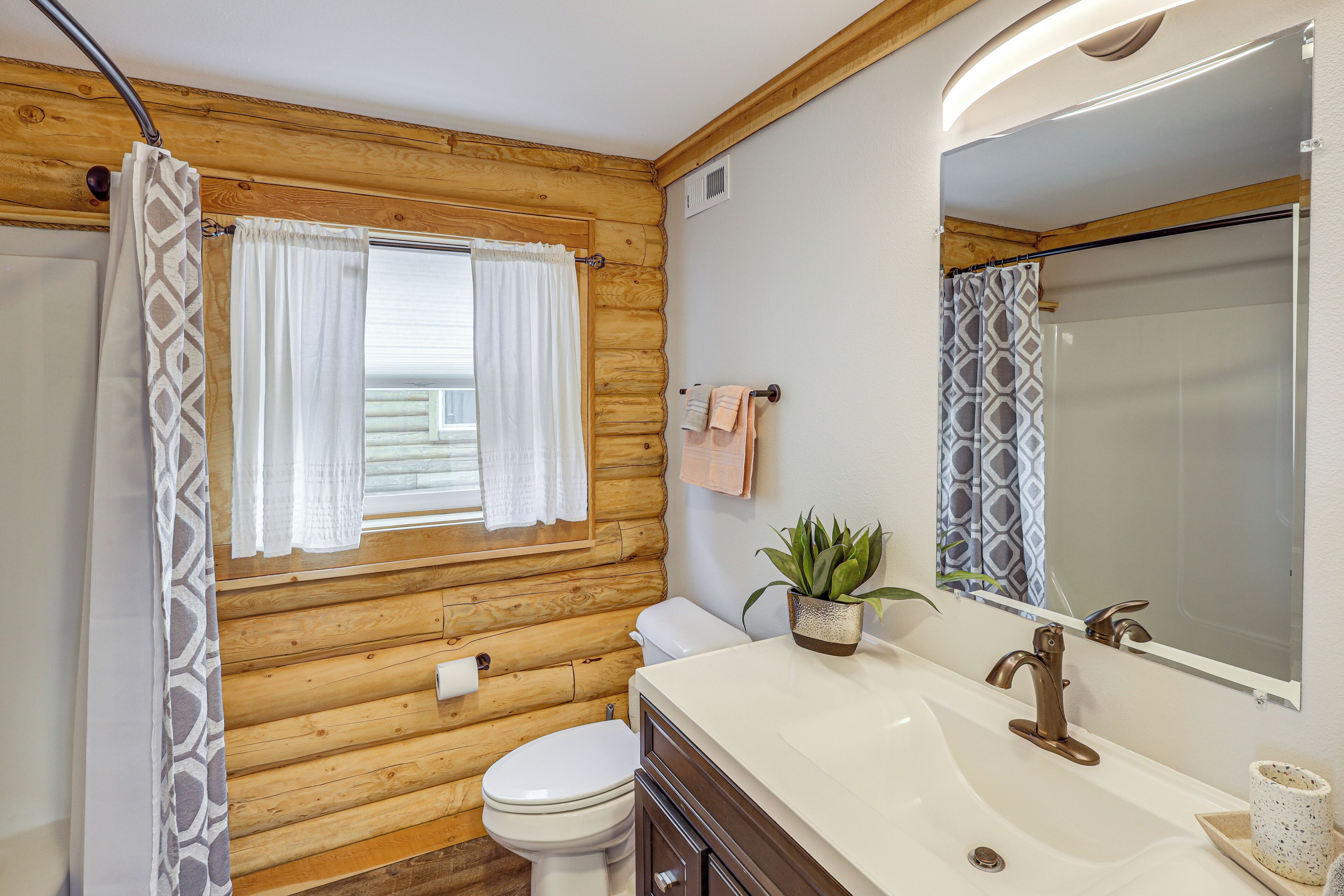 Une salle de bain rustique, aménagée dans une cabane en bois, avec des toilettes, un lavabo et une douche.