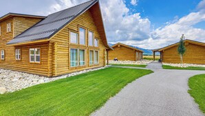 A row of log cabin-style buildings with a gravel driveway leading to a covered walkway.