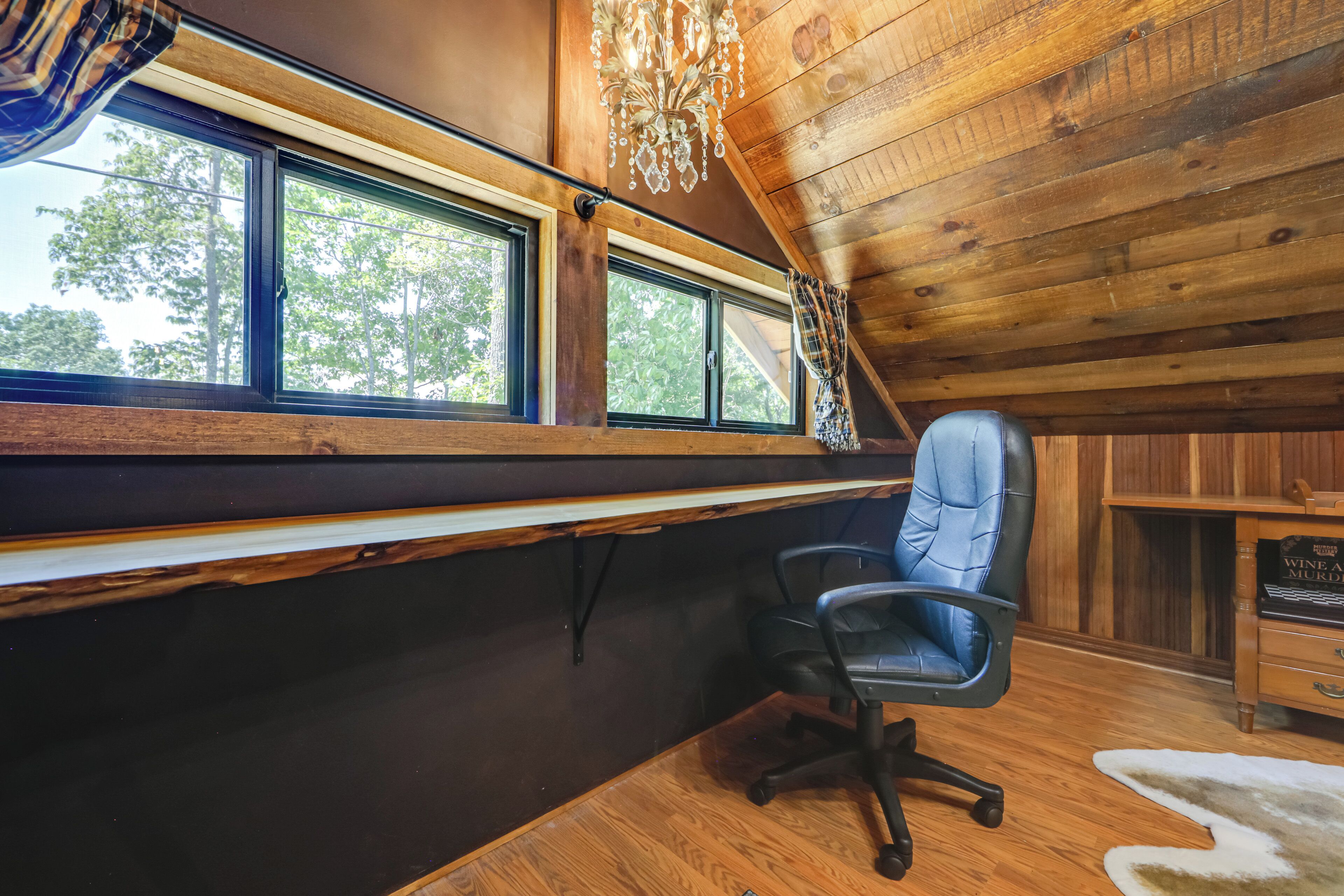 L’intérieur d’une cabine avec un plafond en bois, un bureau, une chaise et de grandes fenêtres.