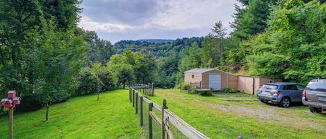 A fenced yard with a wooden deck, a shed, and two parked cars.