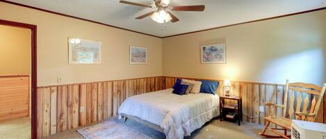 A bedroom with a bed, a ceiling fan, a rocking chair, and a heater.