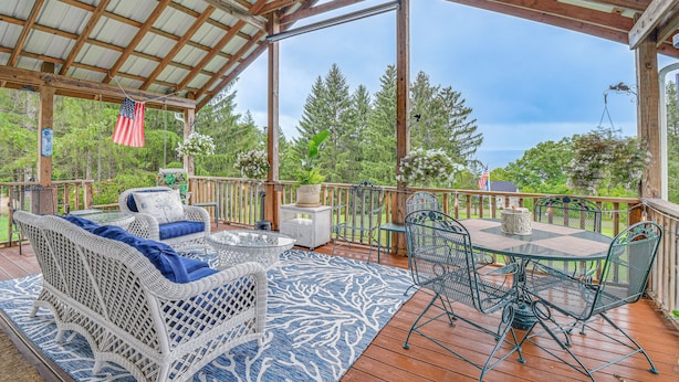 Eine überdachte Terrasse im Freien mit Korbmöbeln, einem Tisch und Stühlen.