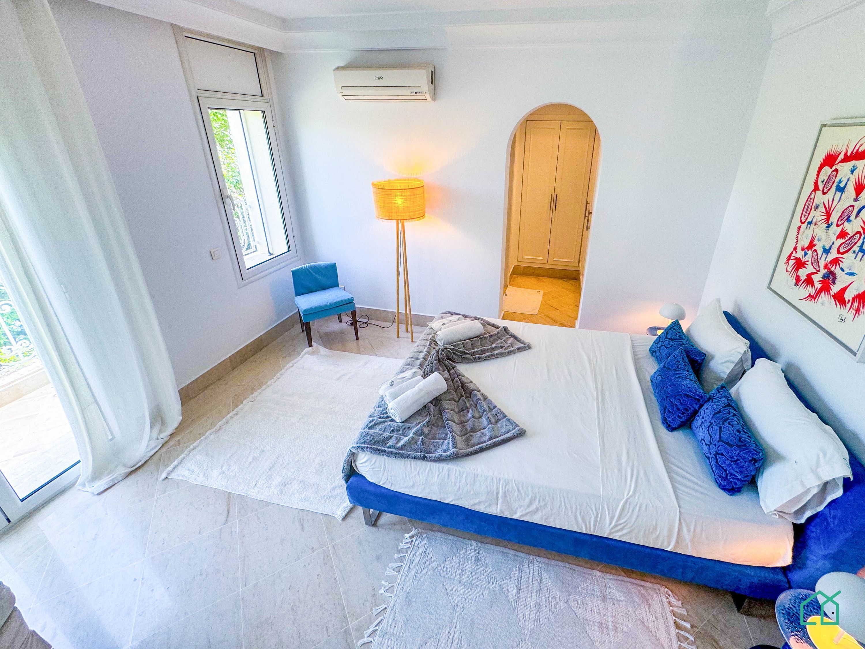 A bedroom with a bed, a chair, a lamp, and a wardrobe.