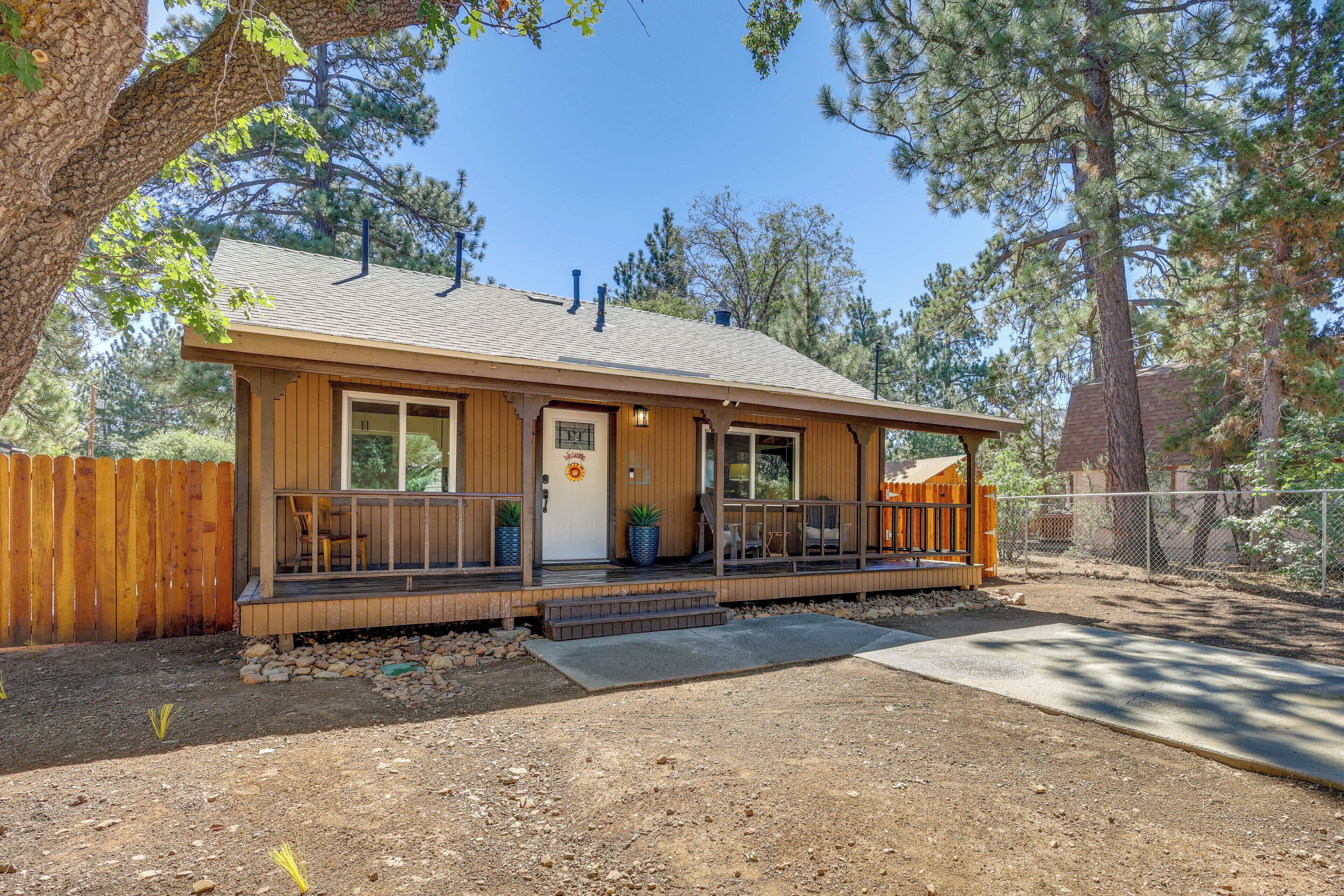 A single-story wooden cabin with a porch, a front door, and a small deck area.