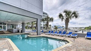 A pool area with lounge chairs, a lifeguard station, and a view of the ocean.