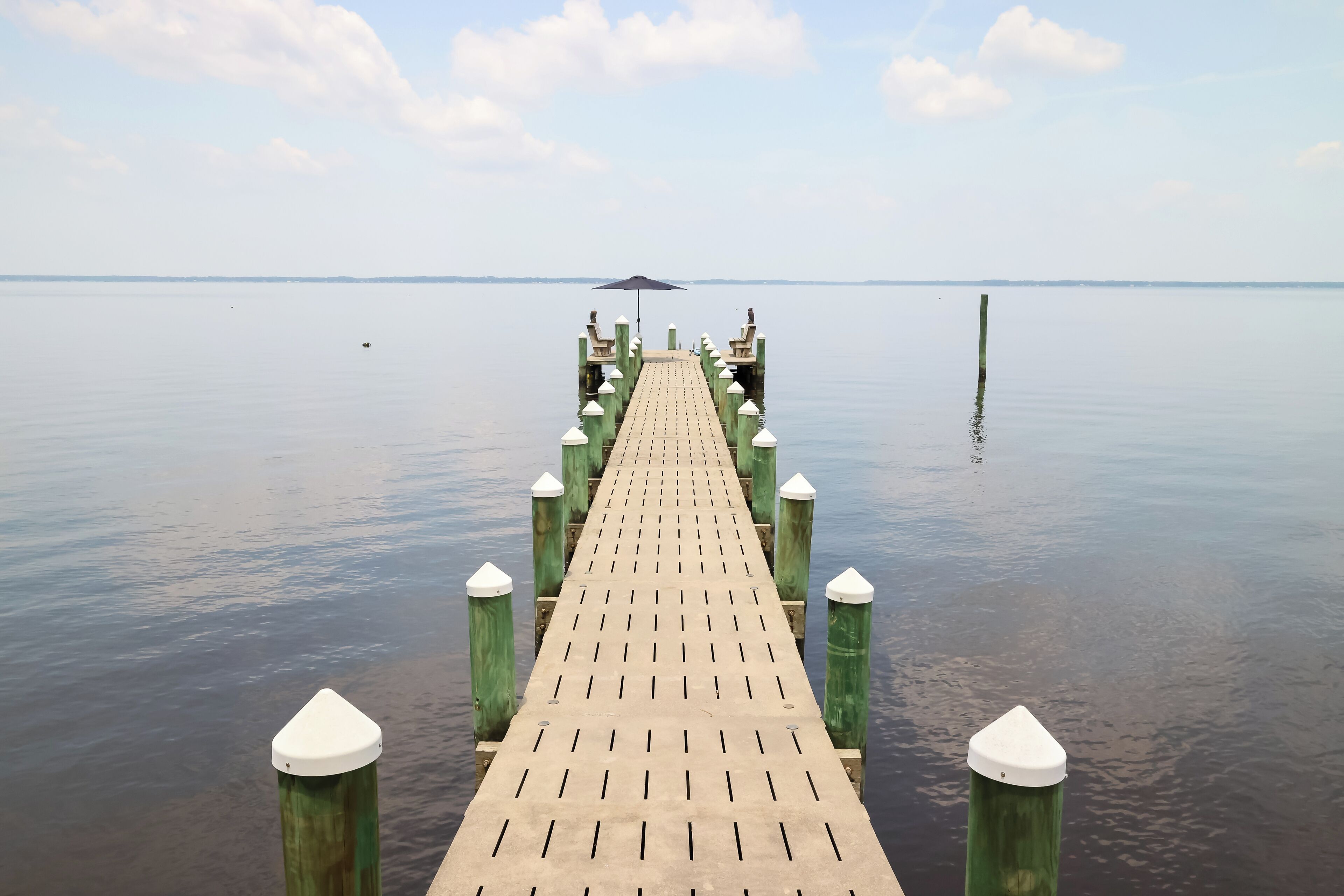 A wooden pier extending into calm water with a clear sky.