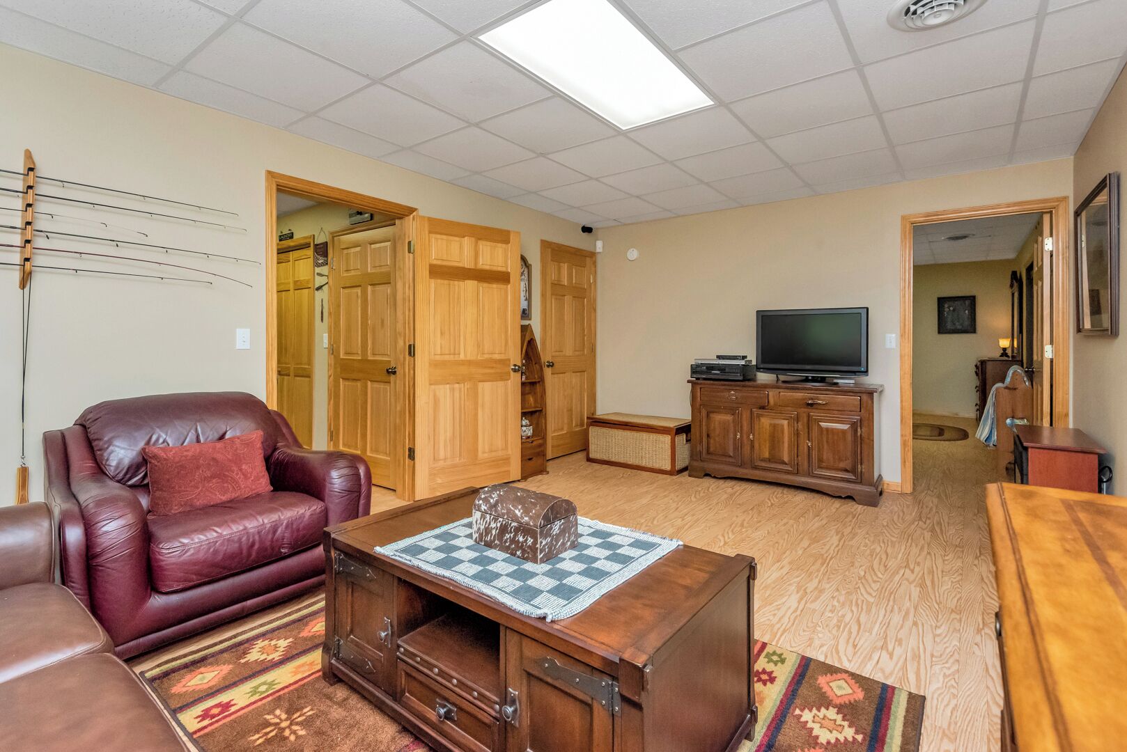 Una sala de estar con un sofá de cuero, una mesa de centro de madera, un televisor sobre un mueble bajo y una alfombra estampada.