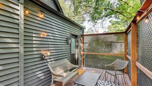 A covered patio with two wicker chairs, a small table, and string lights.