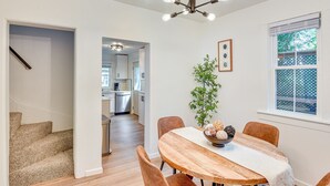 A dining area with a wooden table, chairs, a bowl of decorative items, and a hanging light fixture.