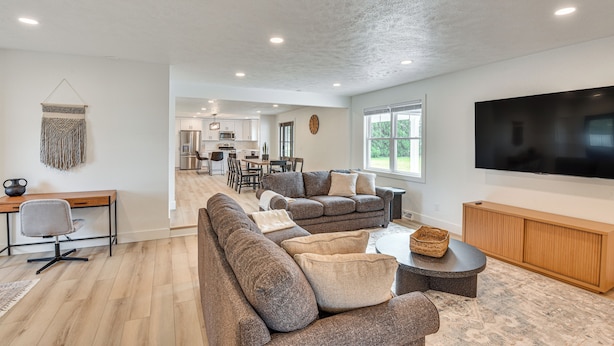 A modern living room with a sectional sofa, a flat-screen TV, and a wooden entertainment unit. - Charming Middlebury Retreat w/ Patio & Fire Pit (Middlebury)