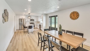 A modern kitchen with white cabinets, stainless steel appliances, and a wooden dining table with chairs. - Charming Middlebury Retreat w/ Patio & Fire Pit (Middlebury)