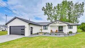 A modern single-story house with a garage, a covered porch with two chairs, and a well-maintained lawn. - Charming Middlebury Retreat w/ Patio & Fire Pit (Middlebury)