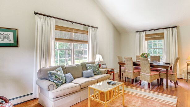 A living room with a sofa, coffee table, dining table with chairs, and large windows with curtains. - 2 Mi to Aiken Horse Park: South Carolina Apt (Aiken)