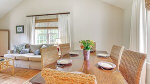 A dining area with a wooden table set for six, surrounded by wicker chairs, a sofa with cushions, and a window with curtains. - 2 Mi to Aiken Horse Park: South Carolina Apt (Aiken)