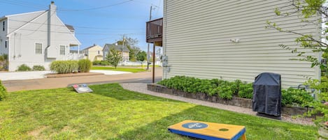 A residential lawn with a lawnmower, a barbecue grill, and a wooden board game.