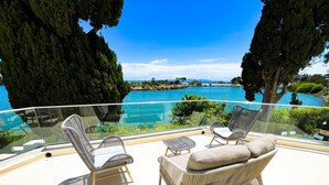 A balcony with wicker furniture overlooking a clear blue sea and lush greenery. - Villa Punique Villa Exceptionnelle Avec vue mer (Carthage)