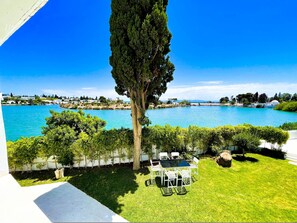 A view of a large body of water with a grassy area and a white table and chairs in the foreground. - Villa Punique Villa Exceptionnelle Avec vue mer (Carthage)