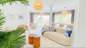 A modern living room with a sofa, wooden side tables, and a dining area with chairs. - Villa Punique Villa Exceptionnelle Avec vue mer (Carthage)
