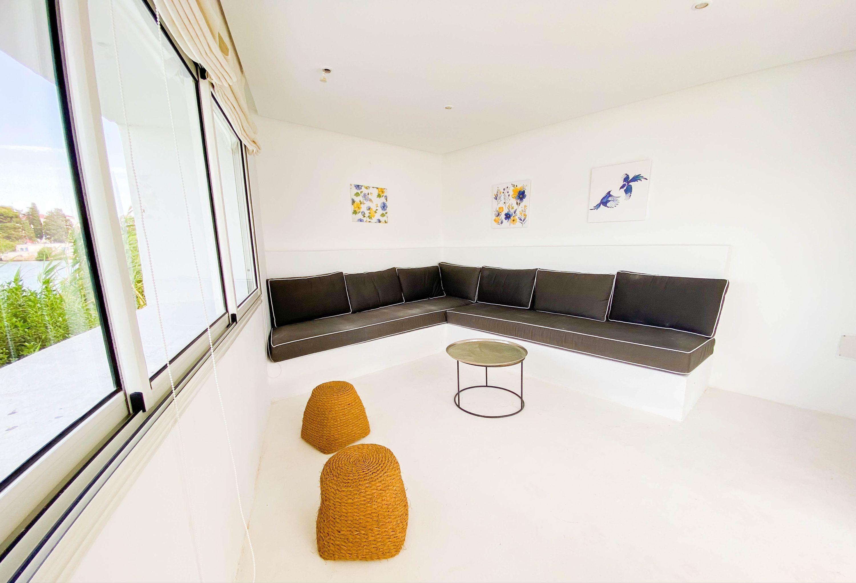 A modern living room with a sectional sofa, two ottomans, a round coffee table, and artwork on the walls.