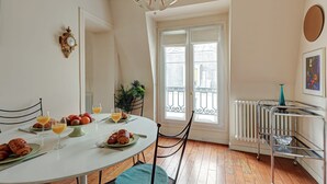 Ein Essbereich mit einem runden Tisch, gedeckt für ein Frühstück, mit Croissants und Orangensaft.