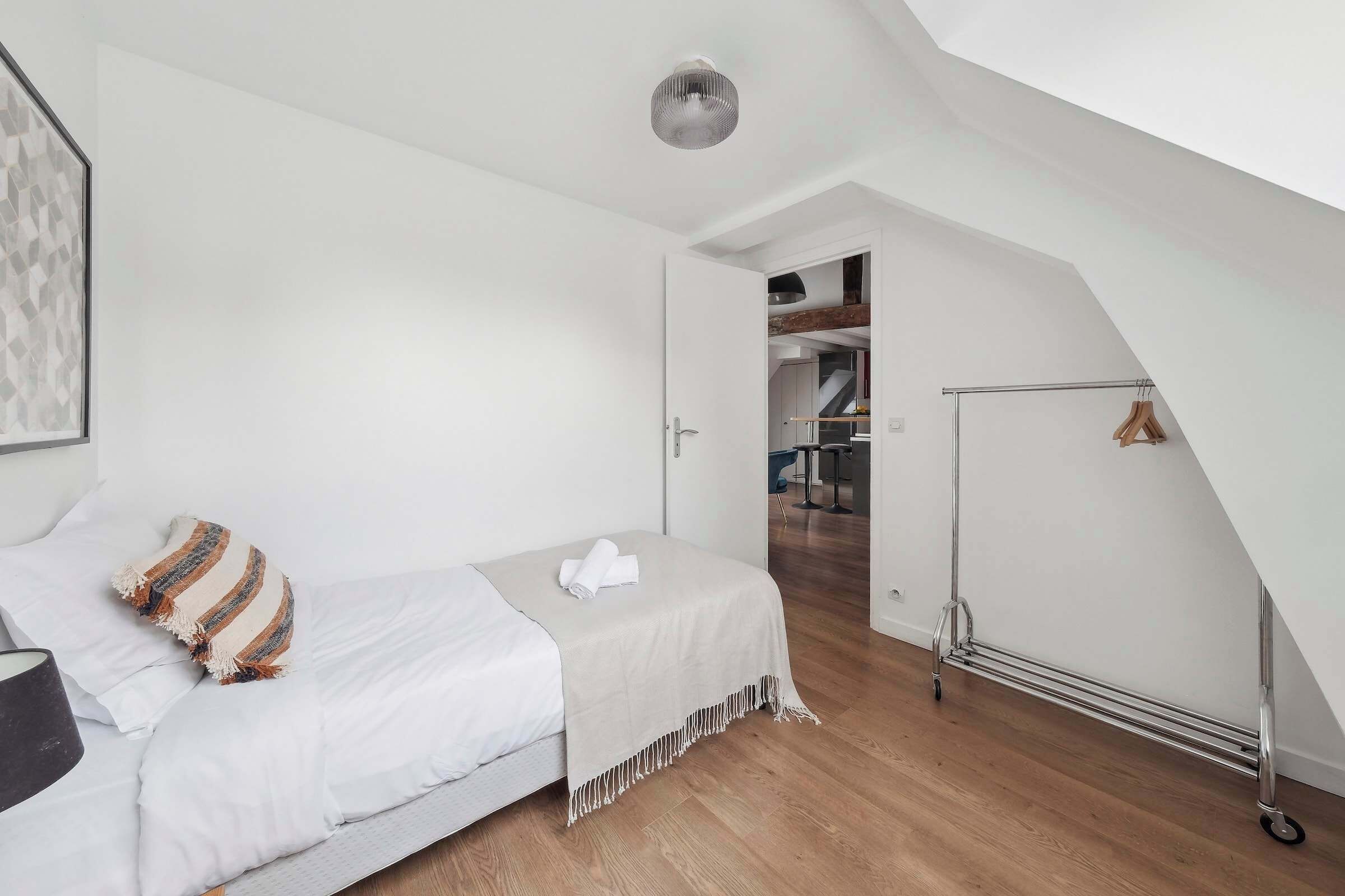 A bedroom with a bed, a hanging light, and a wardrobe.