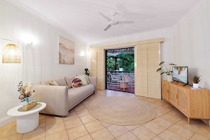 A living room with a sofa, a round coffee table, a cabinet, and a ceiling fan.