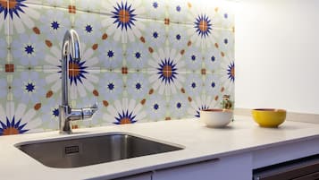 A kitchen with a modern sink, white cabinets, and a decorative backsplash.