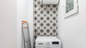 Un lavadero pequeño con una lavadora Bosch, un tendedero y un aire acondicionado de pared.