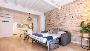 Un espacio habitable compacto con cama, sofá y kitchenette.