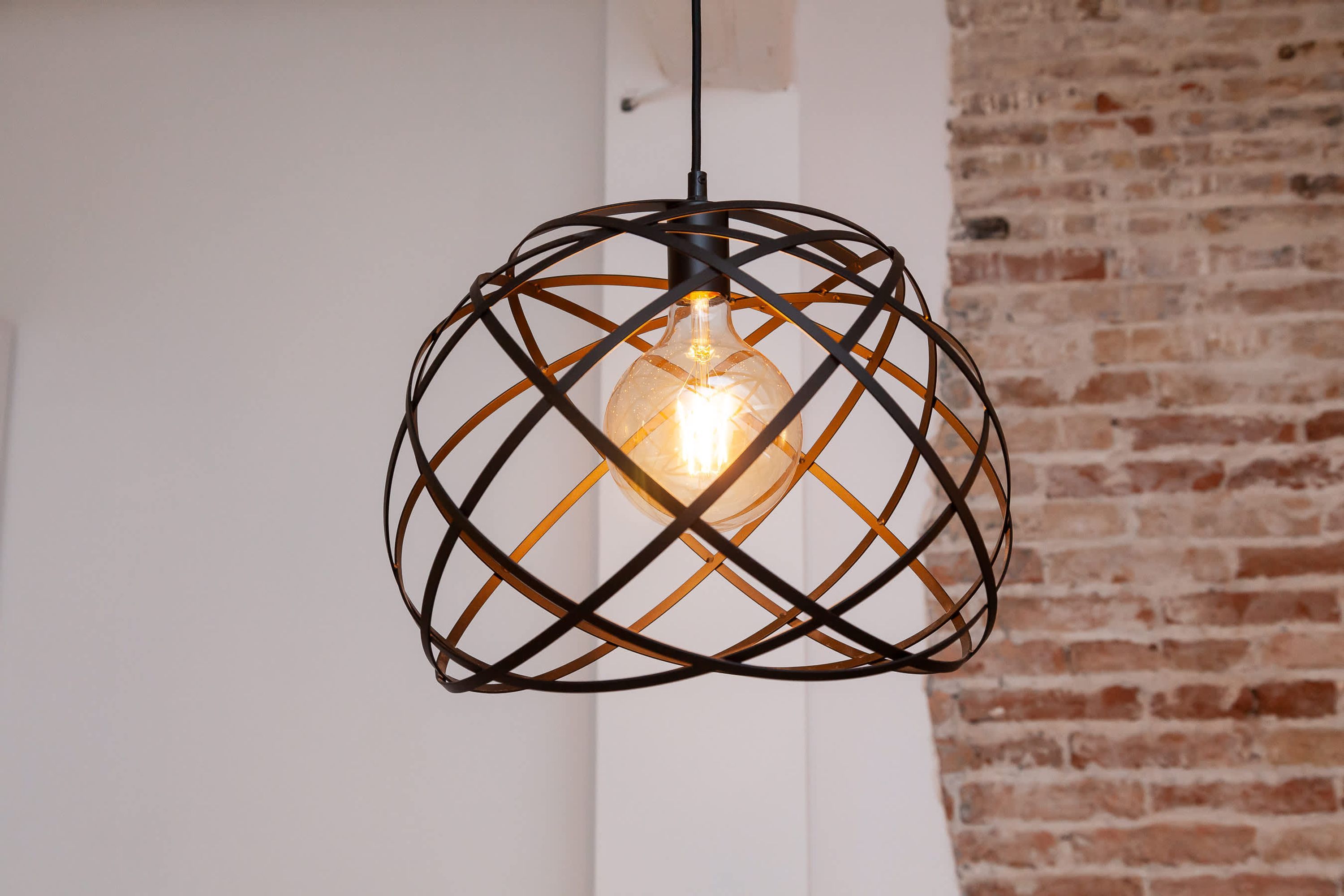 A pendant light fixture with a geometric metal frame and a visible bulb.